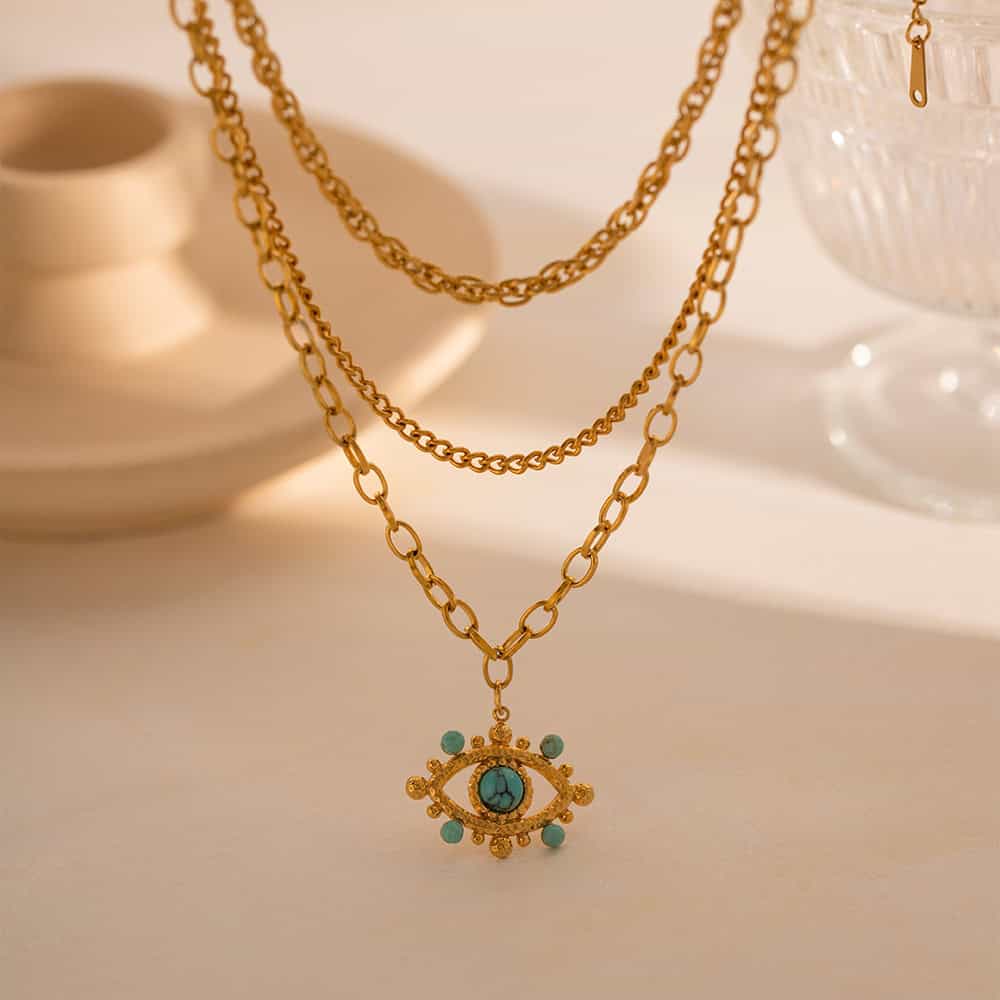 Stylish layered gold necklaces featuring an eye-shaped pendant with turquoise stones, perfect accessory for trendy fashion and jewelry lovers.