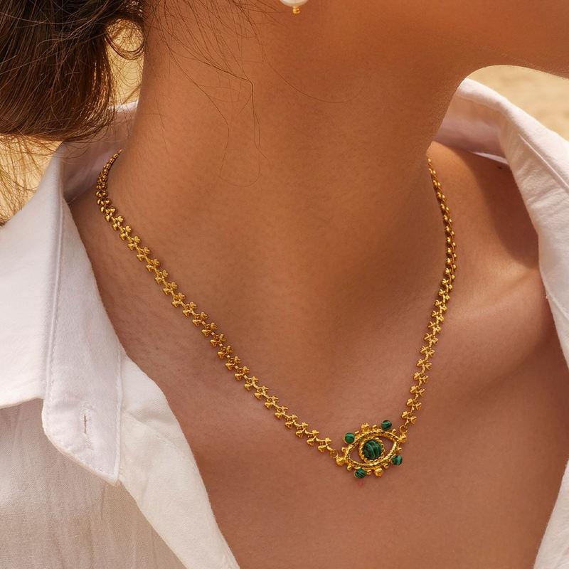 Close-up of a gold chain necklace featuring a pendant with green stones, styled beautifully for women. Perfect for enhancing your jewelry collection at Monalisa Store.