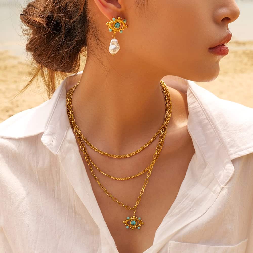 High-quality gold layered chain necklace with eye-shaped pendant, matching pearl earring, perfect for stylish women and jewelry lovers.