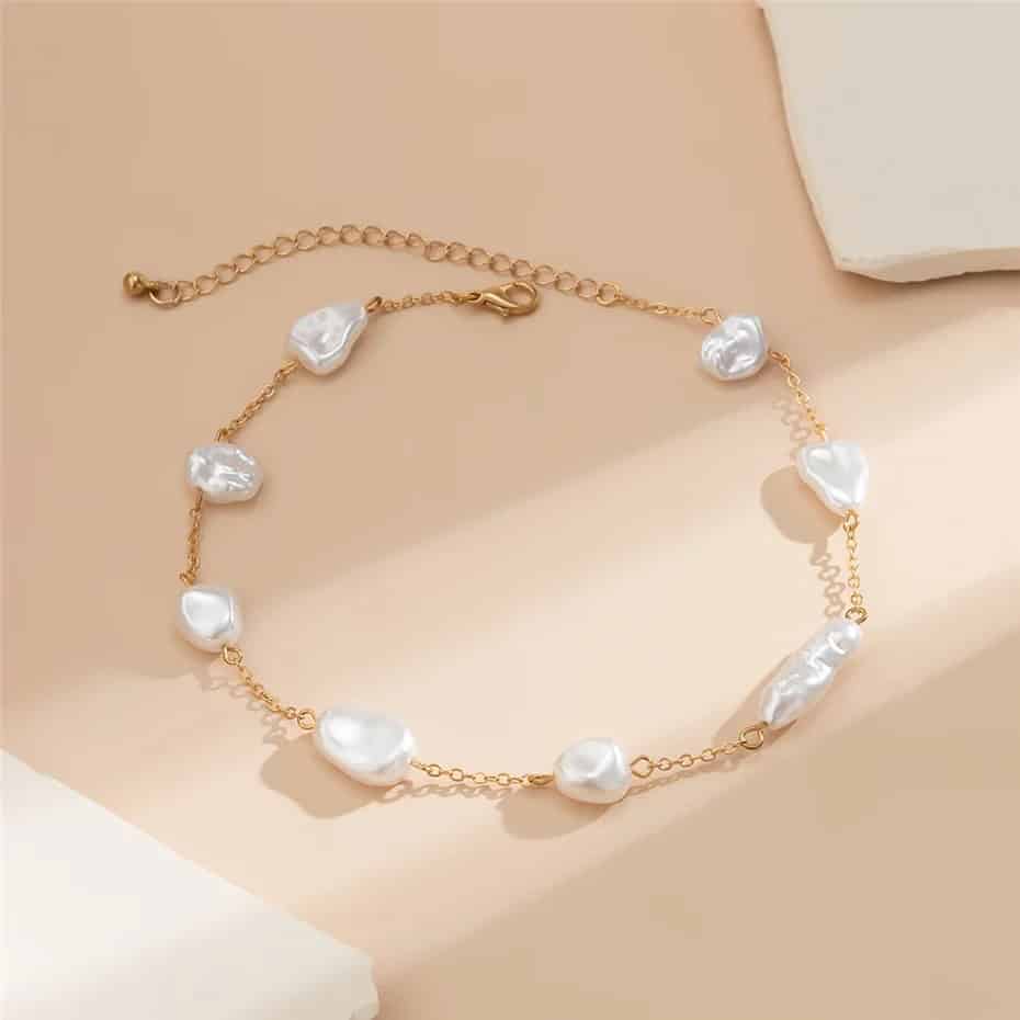 Gold chain with white freshwater pearls and heart-shaped pearl accents, perfect for stylish accessorizing and gifts.