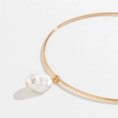 Close-up of a gold loop necklace featuring a dangling white pearl, ideal for jewelry lovers. Perfect accessory for a sophisticated look, available at Monalisa Medical store.