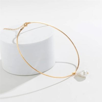 Gold choker necklace with a dangling pearl for stylish elegance and sophistication. Perfect accessory for formal or casual fashion statements.