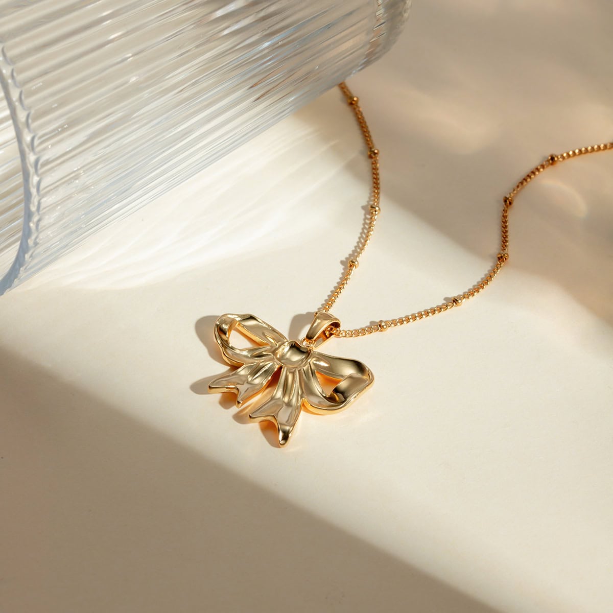 Delicate gold necklace featuring a bow pendant, perfect for stylish accessorizing. Shop luxury jewelry collection at Monalisa Store for timeless elegance.