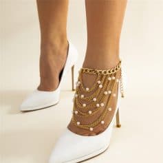 Stylish gold chain anklet with pearls, layered with chains on white stiletto heels, perfect for fashionable foot accessories and jewelry.