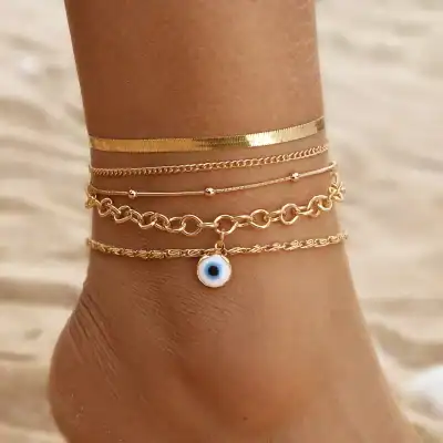 Delicate gold layered bracelets with a charming blue eye charm on a tanned wrist, perfect for stylish accessories and jewelry shopping at Monalisa Store.