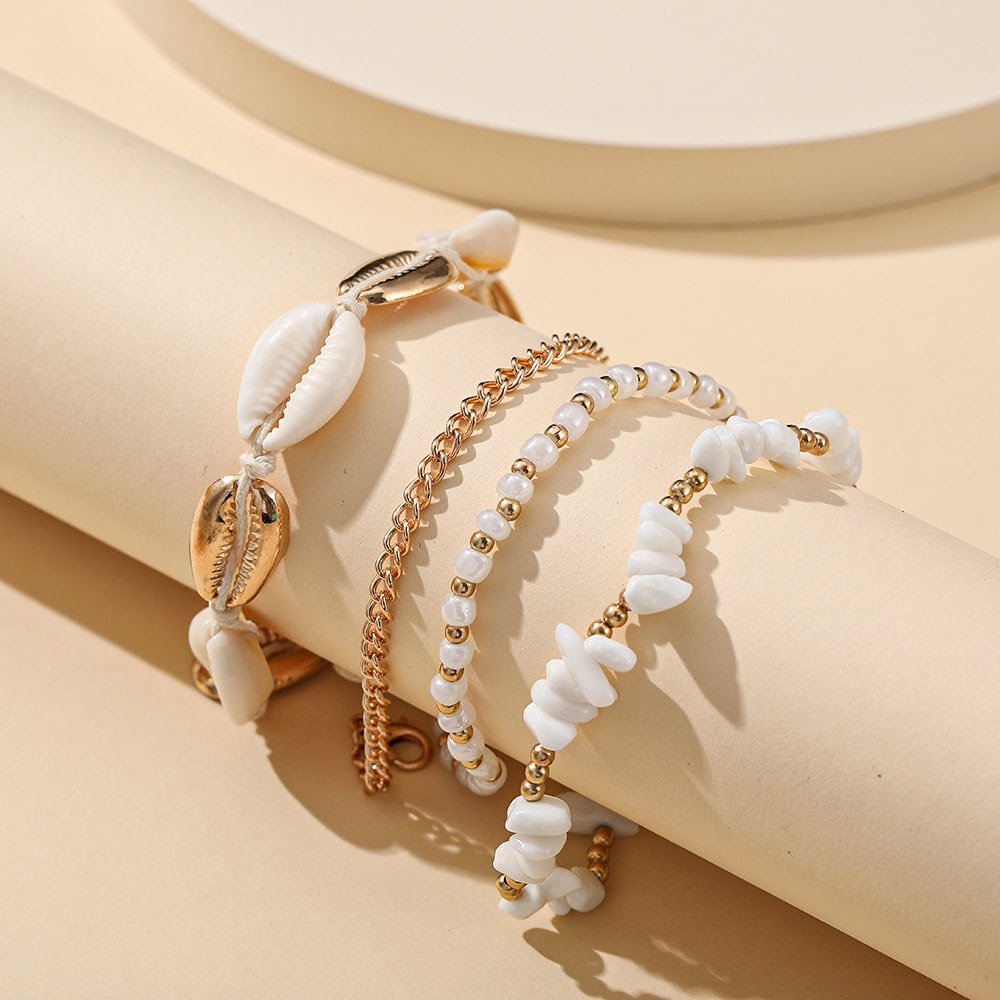 Beautiful seashell-inspired jewelry displayed on a cylindrical surface, featuring white shell beads and gold chains, perfect for beach and summer accessories.