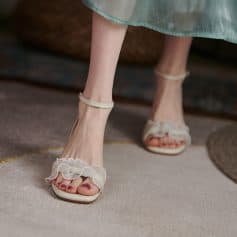 Close-up of women's stylish open-toe sandals with ruffle details, featuring ankle straps and a comfortable heel for everyday fashion and special occasions.