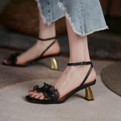 Elegant black open-toe high heels with ankle straps and unique gold block heels, perfect for fashion-forward women seeking trendy footwear for any occasion.