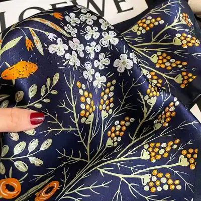 Vibrant navy floral dress fabric with white and orange flower and berry print, perfect for fashion and sewing projects.