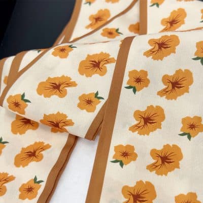 Bright orange floral fabric pattern with green leaves, suitable for custom suits, dresses, and fashion accessories. Premium quality textile perfect for stylish apparel and sewing projects.