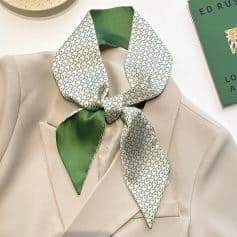 Luxurious silk scarf with houndstooth pattern and emerald green accents, styled over a white blazer for a sophisticated look. Perfect for enhancing optical fashion and accessories.
