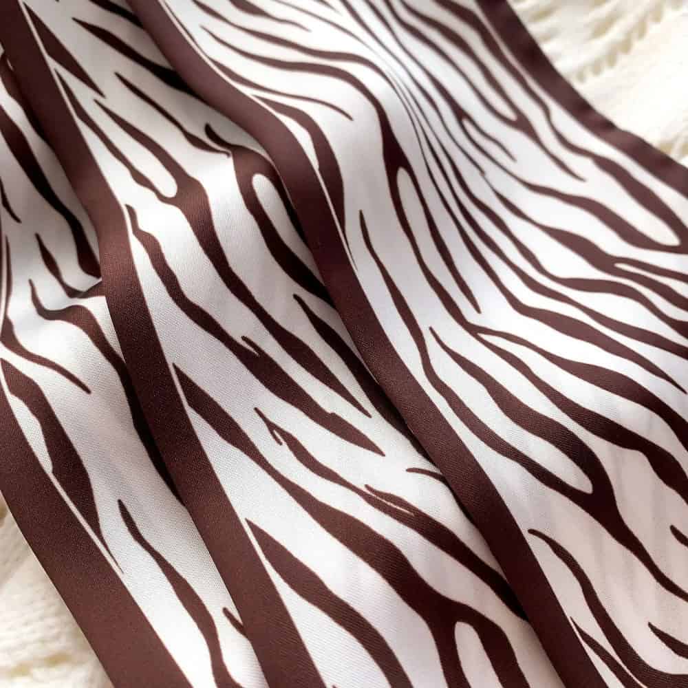Zebra pattern fabric featuring bold brown and white stripes, perfect for fashion and interior decor accessories. Durable and stylish material ideal for sewing projects or statement clothing pieces.