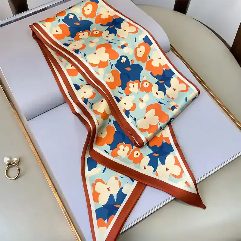 Vibrant floral patterned silk scarf with orange, navy blue, and cream colors, perfect for stylish accessories and enhancing your outfit.