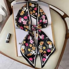 Elegant floral patterned silk scarf with vibrant pink, white, and yellow flowers on a black background, perfect for fashion accessories and stylish embellishments.