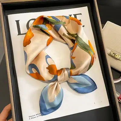 Luxurious floral silk scarf in vibrant orange, green, blue, and cream colors, ideal for stylish women’s fashion accessories and personal adornment.
