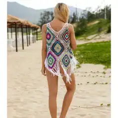 A woman wearing a colorful crochet beach cover-up on the sand with scenic mountains and greenery in the background. Perfect for summer beachwear and vacation styles.
