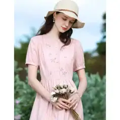Beautiful young woman in a pink embroidered dress with a sun hat holding a bouquet of flowers, perfect for stylish summer outings and fashion accessories.