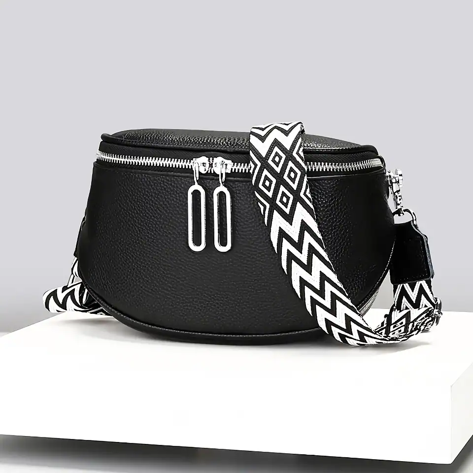 Stylish black leather crossbody bag with silver zippers and a bold black and white patterned strap, perfect for fashion-forward accessories and daily convenience.