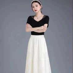 Close-up of a fashionable woman wearing a black top with sheer detailing and a flowing white skirt, showcasing chic and stylish fashion perfect for modern women.