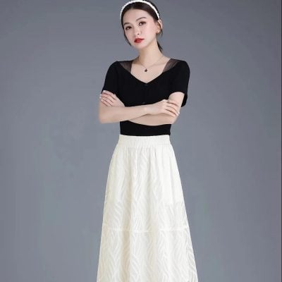 Close-up of a fashionable woman wearing a black top with sheer detailing and a flowing white skirt, showcasing chic and stylish fashion perfect for modern women.