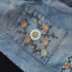 Detailed floral embroidery on denim pocket, stylish and trendy women's casual wear. Perfect for fashion-forward looks.