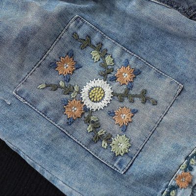 Detailed floral embroidery on denim pocket, stylish and trendy women's casual wear. Perfect for fashion-forward looks.