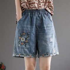 Comfortable distressed denim shorts with floral embroidery and rolled hem, perfect for casual wear and summer outings. Features an elastic waistband for a relaxed fit.