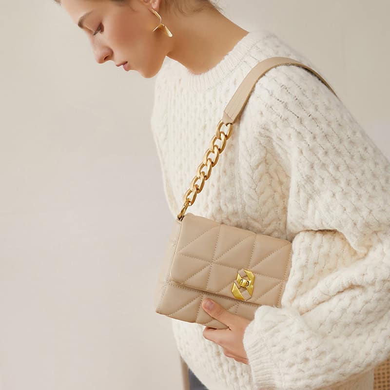 Stylish beige quilted handbag with gold chain strap and hardware, perfect for fashion-forward accessories. Ideal for women seeking elegant and functional bags.