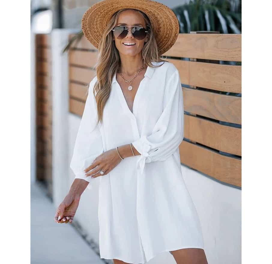 Woman in white summer dress wearing a sun hat and sunglasses, enjoying a sunny day outdoors at Monalisa Store, showcasing stylish eyewear and fashionable accessories.