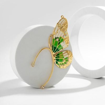 Elegant gold butterfly wing brooch with green enamel and sparkling rhinestones, perfect for fashion accessories and jewelry lovers.