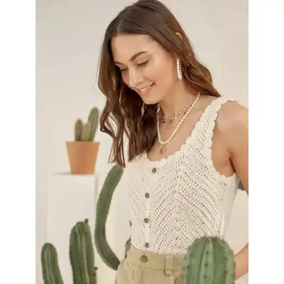 Elegant woman wearing a crochet sleeveless top from Monalisa Store, paired with pearl jewelry, standing in a stylish, modern setting with potted cacti, showcasing trendy summer fashion.
