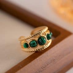 A luxurious gold ring featuring three vibrant green malachite stones set in a detailed braided gold band, perfect for jewelry enthusiasts and collectors seeking unique, stylish accessories.