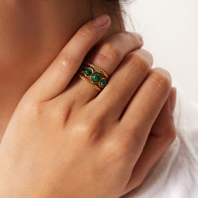 Close-up of a woman’s hand wearing a stylish gold ring with green malachite stones, showcasing luxurious jewelry options available at Monalisa Store for women.