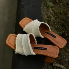Stylish beige slide sandals with textured fabric straps and cushioned soles, perfect for casual wear or summer outings.