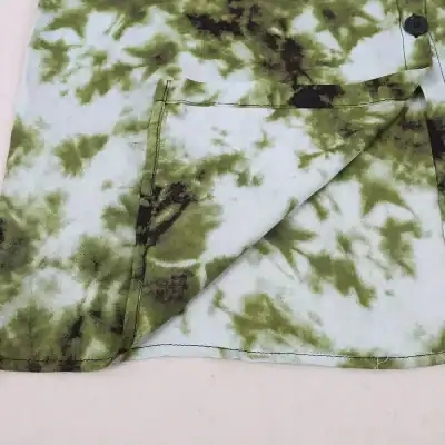 Vibrant tie-dye scrub top featuring green and black leaf patterns, perfect for healthcare workers seeking stylish, comfortable, and functional medical attire.