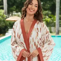 Beautiful woman smiling in feather print kimono by the poolside, showcasing Monalisa Store’s fashionable, comfortable resort wear and elegant women’s robes.