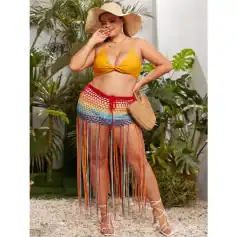 Detailed description of a woman wearing colorful crochet shorts, a yellow bikini top, and stylish white lace-up heels, accessorized with a straw hat and woven handbag, standing among lush tropical plants.