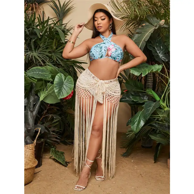 Beautiful woman in tropical swimsuit with beach accessories, surrounded by lush greenery for a summer fashion photo shoot.