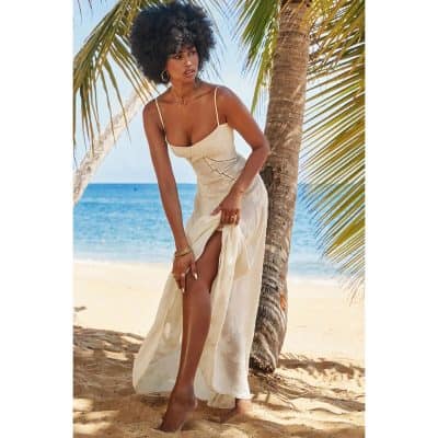 Young woman in summer dress by the beach, enjoying sunny weather.