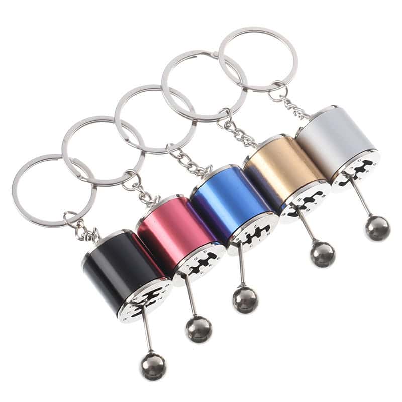 High-quality motorcycle-themed keychains in various colors including black, red, blue, gold, and silver, featuring detailed engine design and durable metal construction, perfect for motorcycle enthusiasts.