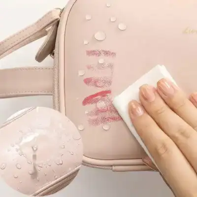 Pink makeup bag with water droplets and kiss mark design, being wiped clean with a tissue, highlighting cosmetic organization and beauty essentials.