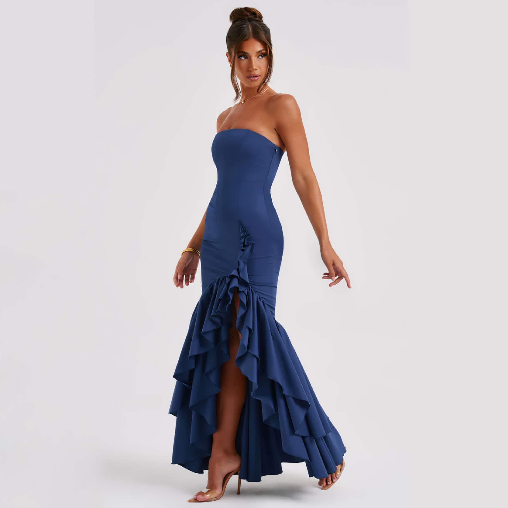 A stunning woman wearing a strapless navy blue gown with dramatic ruffles and a high slit, perfect for formal events, parties, or celebrations.