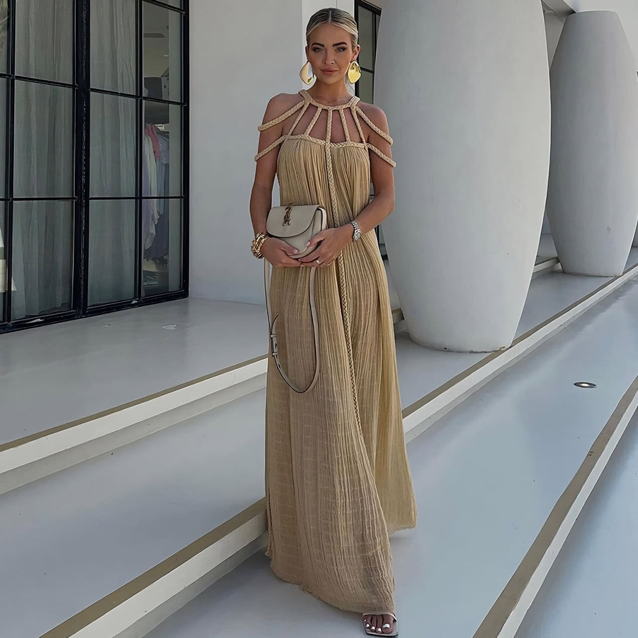 Stylish beige maxi dress with unique shoulder cutouts and intricate detailing, perfect for summer events and outdoor occasions.
