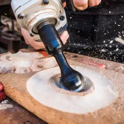 A close-up of a power drill making a circular hole in a wooden surface, with wood dust flying around, demonstrating woodworking craftsmanship.