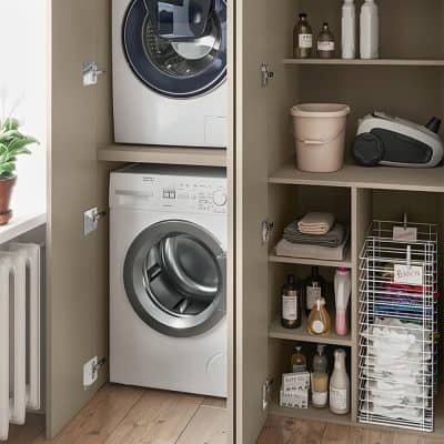 Efficient laundry room with stacked washing machine and dryer, organized shelves with detergent bottles, laundry baskets, and cleaning supplies for a tidy home environment.