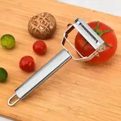 A stainless steel tomato peeler with sharp blades for easy peeling of tomatoes, on a wooden cutting board alongside cherry and green tomatoes, perfect for food preparation.