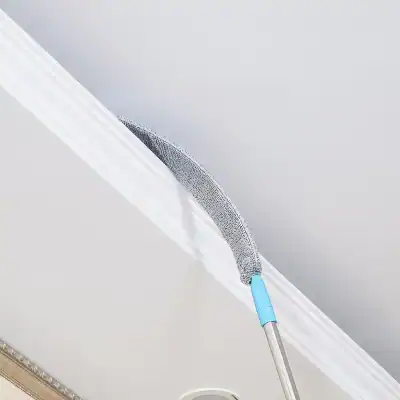 High-quality microfiber duster cleaning ceiling and wall surfaces, ideal for removing dust and cobwebs efficiently in home or office environments.