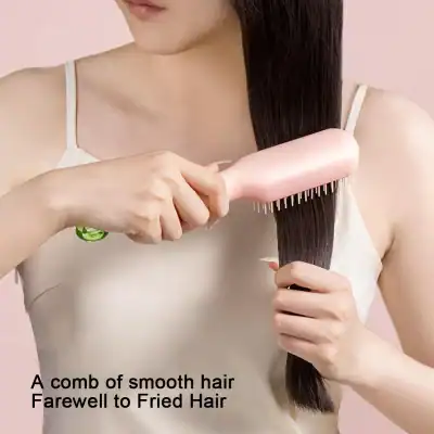 Close-up of woman brushing long, smooth hair with a pink hairbrush, emphasizing hair health and beauty.