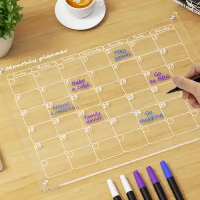 Organized monthly planner on a transparent acrylic sheet with handwritten notes for appointments like family dinner, bake a cake, and BBQ, ideal for efficient scheduling and time management.