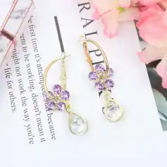 Beautiful gold earrings with purple gemstones and teardrop clear stones, perfect for elegant occasions and jewelry lovers.